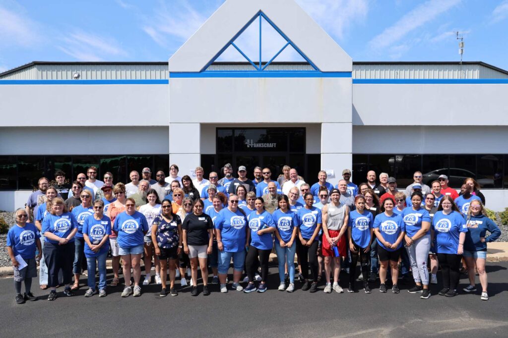 Hankscraft Inc. staff celebrate 75 years incorporated and pose for a photo in front of the headquarters building in Reedsburg, WI.