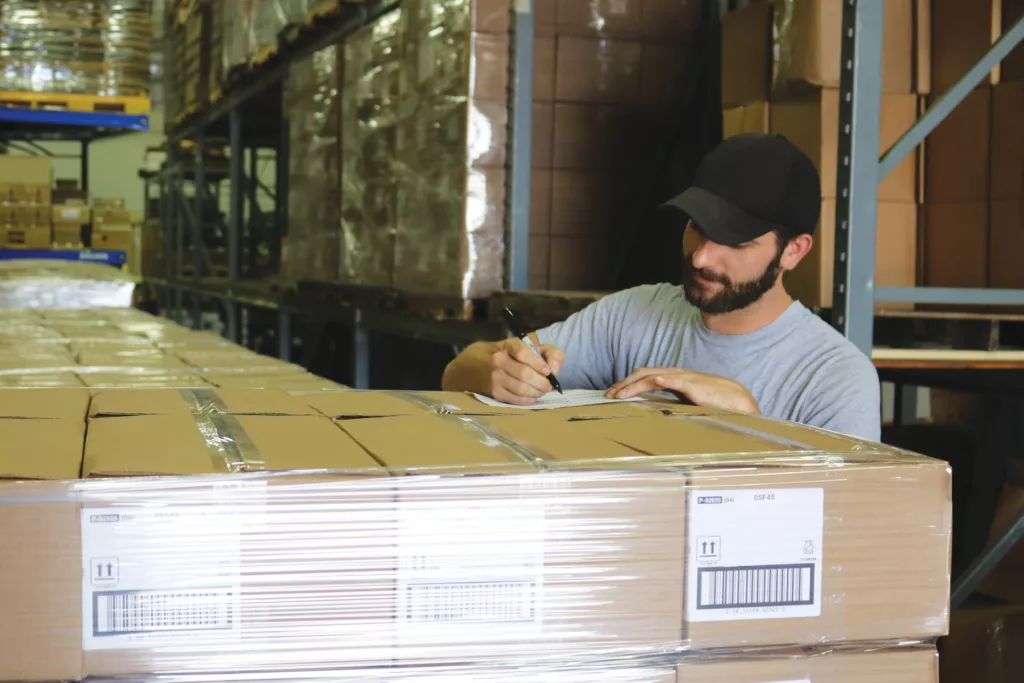 Man writing on shipping pallet for logistics and fulfillment services of Hanskcraft's contract manufacturing business.